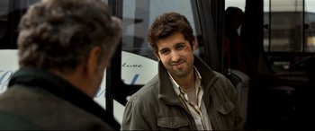 Movie still from “The Wild Pear Tree” (2018), directed by Nuri Bilge Ceylan – A man with a beard is smiling for the camera; Close Up shot, Over the shoulder angle