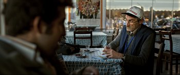 Movie still from “The Wild Pear Tree” (2018), directed by Nuri Bilge Ceylan – Two people sitting at a table in a restaurant; Medium shot, Over the shoulder angle