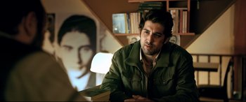 Movie still from “The Wild Pear Tree” (2018), directed by Nuri Bilge Ceylan – A man sitting in front of a picture of a woman; Medium shot, Over the shoulder angle