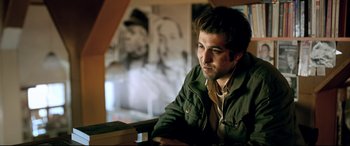 Movie still from “The Wild Pear Tree” (2018), directed by Nuri Bilge Ceylan – A man sitting at a table with a book in front of him; Medium shot, Low angle