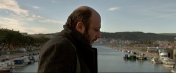 Movie still from “The Wild Pear Tree” (2018), directed by Nuri Bilge Ceylan – A man with a bald head looking out at the water; Close Up shot, Low angle