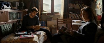 Movie still from “The Wild Pear Tree” (2018), directed by Nuri Bilge Ceylan – A man sitting on top of a bed reading a book; Medium shot, Over the shoulder angle