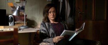 Movie still from “The Wild Pear Tree” (2018), directed by Nuri Bilge Ceylan – A woman sitting in a chair holding an open book; Medium shot, High angle