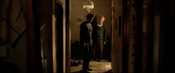 Movie still from “The Wild Pear Tree” (2018), directed by Nuri Bilge Ceylan – Two men standing next to each other in a room; Wide shot, Over the shoulder angle