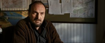 Movie still from “The Wild Pear Tree” (2018), directed by Nuri Bilge Ceylan – A person sitting in front of a wall; Close Up shot, Over the shoulder angle