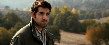 Movie still from “The Wild Pear Tree” (2018), directed by Nuri Bilge Ceylan – A person wearing a jacket near a forest; Close Up shot, Low angle
