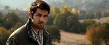 Movie still from “The Wild Pear Tree” (2018), directed by Nuri Bilge Ceylan – A person wearing a jacket near a forest; Close Up shot, Low angle