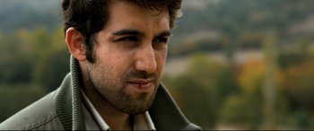 Movie still from “The Wild Pear Tree” (2018), directed by Nuri Bilge Ceylan – A man's face with trees in the background; Close Up shot, Low angle