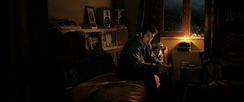 Movie still from “The Wild Pear Tree” (2018), directed by Nuri Bilge Ceylan – A man sitting on top of a bed next to a window; Medium shot, High angle