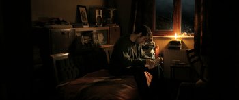 Movie still from “The Wild Pear Tree” (2018), directed by Nuri Bilge Ceylan – A man sitting on a bed looking at his cell phone; Wide shot, High angle
