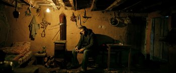 Movie still from “The Wild Pear Tree” (2018), directed by Nuri Bilge Ceylan – A man sitting on a chair in a room; Wide shot, High angle
