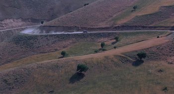 Movie still from “The Wind Will Carry Us” (1999), directed by Abbas Kiarostami – An aerial view of a dirt road with a car on it; Extreme Wide shot, High angle