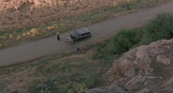 Movie still from “The Wind Will Carry Us” (1999), directed by Abbas Kiarostami – A group of people walking down a dirt road near a car; Extreme Wide shot, High angle