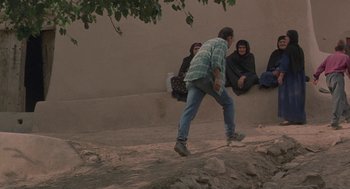 Movie still from “The Wind Will Carry Us” (1999), directed by Abbas Kiarostami – A man riding a skate board on top of a hill; Wide shot, High angle