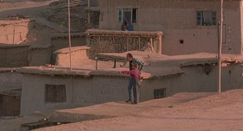 Movie still from “The Wind Will Carry Us” (1999), directed by Abbas Kiarostami – A man and a child standing on top of a dirt hill; Extreme Wide shot, High angle