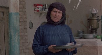 Movie still from “The Wind Will Carry Us” (1999), directed by Abbas Kiarostami – An older woman holding a tray in her hands; Medium shot, Low angle