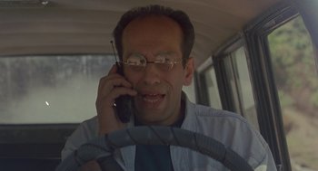 Movie still from “The Wind Will Carry Us” (1999), directed by Abbas Kiarostami – A man with glasses talking on a cell phone while sitting in a car; Close Up shot, Low angle