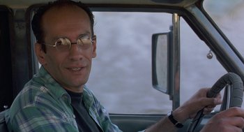 Movie still from “The Wind Will Carry Us” (1999), directed by Abbas Kiarostami – A man driving in a car wearing glasses; Close Up shot, Low angle