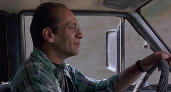 Movie still from “The Wind Will Carry Us” (1999), directed by Abbas Kiarostami – A man in a plaid shirt driving a car; Close Up shot, Low angle