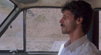 Movie still from “The Wind Will Carry Us” (1999), directed by Abbas Kiarostami – A man with a mustache sitting in a car; Close Up shot, Low angle