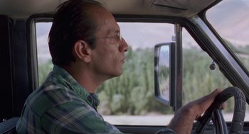 Movie still from “The Wind Will Carry Us” (1999), directed by Abbas Kiarostami – A man sitting in the driver's seat of a car looking out the window; Close Up shot, Low angle