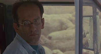 Movie still from “The Wind Will Carry Us” (1999), directed by Abbas Kiarostami – A person wearing glasses near a window; Close Up shot, Over the shoulder angle