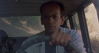 Movie still from “The Wind Will Carry Us” (1999), directed by Abbas Kiarostami – A man driving a car holding a steering wheel; Close Up shot, Low angle