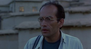 Movie still from “The Wind Will Carry Us” (1999), directed by Abbas Kiarostami – A person wearing glasses and a jacket; Close Up shot, Low angle