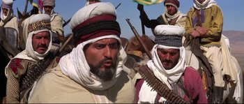 Movie still from “The Wind and the Lion” (1975), directed by John Milius – A group of men standing next to each other holding guns; Medium shot, Low angle