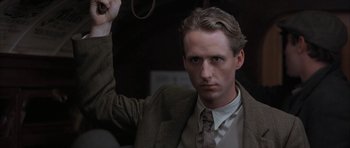 Movie still from “The Wings of the Dove” (1997), directed by Iain Softley – A man in a suit and tie holding a whip in his hand; Close Up shot, Low angle