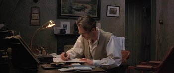 Movie still from “The Wings of the Dove” (1997), directed by Iain Softley – A man sitting at a desk writing on a piece of paper; Medium shot, High angle