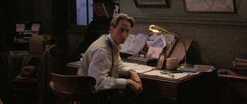 Movie still from “The Wings of the Dove” (1997), directed by Iain Softley – A man sitting at a desk in front of papers; Medium shot, High angle