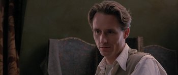 Movie still from “The Wings of the Dove” (1997), directed by Iain Softley – A person sitting in a chair wearing a suit; Close Up shot, Low angle