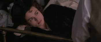 Movie still from “The Wings of the Dove” (1997), directed by Iain Softley – A woman laying in a bed looking at the camera; Close Up shot, High angle