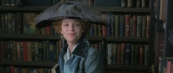 Movie still from “The Wings of the Dove” (1997), directed by Iain Softley – A woman wearing a hat in front of a book shelf; Close Up shot, Low angle