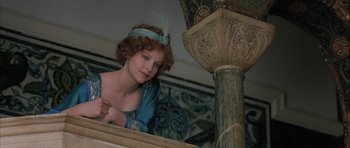 Movie still from “The Wings of the Dove” (1997), directed by Iain Softley – A woman in a blue dress with a feather headband; Medium shot, Low angle
