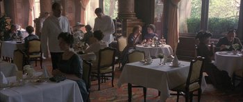 Movie still from “The Wings of the Dove” (1997), directed by Iain Softley – A group of people sitting at tables in a room; Wide shot, High angle
