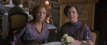 Movie still from “The Wings of the Dove” (1997), directed by Iain Softley – Two women sitting at a table with a bouquet of flowers; Medium shot, High angle
