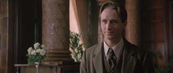 Movie still from “The Wings of the Dove” (1997), directed by Iain Softley – A man in a suit and tie smiling for the camera; Close Up shot, Low angle