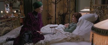 Movie still from “The Wings of the Dove” (1997), directed by Iain Softley – Two women sitting on a bed talking to each other; Medium shot, High angle
