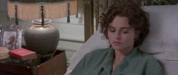 Movie still from “The Wings of the Dove” (1997), directed by Iain Softley – A woman sitting in a chair with her eyes closed; Close Up shot, High angle