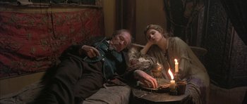 Movie still from “The Wings of the Dove” (1997), directed by Iain Softley – An older man and a young woman sitting next to each other on a couch; Medium shot, High angle