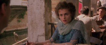 Movie still from “The Wings of the Dove” (1997), directed by Iain Softley – A woman sitting at a table with a glass of water; Close Up shot, Over the shoulder angle