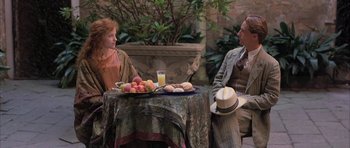 Movie still from “The Wings of the Dove” (1997), directed by Iain Softley – A man and a woman sitting at a table with a plate of fruit; Medium shot, Over the shoulder angle