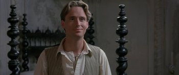 Movie still from “The Wings of the Dove” (1997), directed by Iain Softley – A man with long blonde hair standing in front of a wall; Close Up shot, Over the shoulder angle