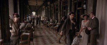 Movie still from “The Wings of the Dove” (1997), directed by Iain Softley – A group of people are walking around a restaurant; Wide shot, High angle