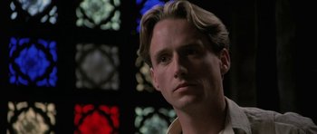 Movie still from “The Wings of the Dove” (1997), directed by Iain Softley – A person in front of stained glass windows; Close Up shot, Low angle