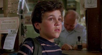 Movie still from “The Wizard” (1989), directed by Todd Holland – A young boy is looking at the camera while sitting in front of a man; Close Up shot, Low angle