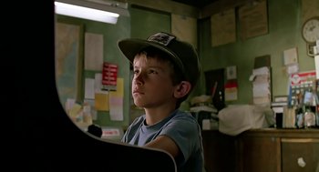Movie still from “The Wizard” (1989), directed by Todd Holland – A young boy wearing a hat sitting at a desk; Close Up shot, Low angle