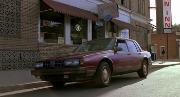 Movie still from “The Wizard” (1989), directed by Todd Holland – An old car parked in front of a building; Wide shot, Low angle